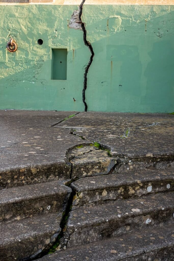 pexels photo 10587372 Detailed view of a cracked concrete wall and steps outdoors, showing damage and weathering.