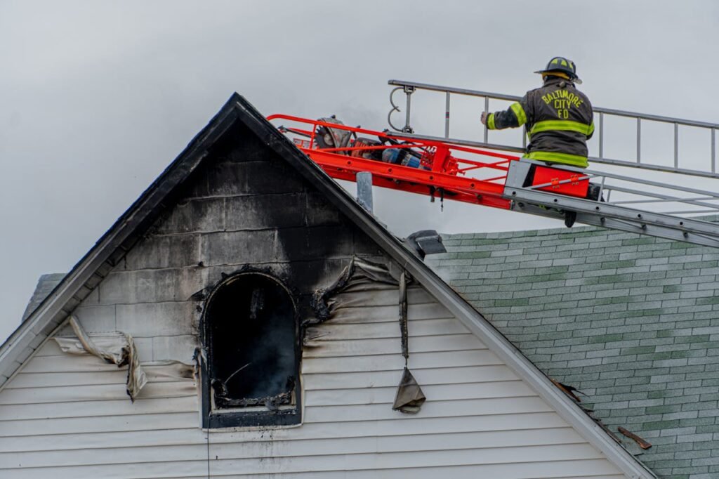pexels photo 6357619 Firefighter on ladder tackling a residential roof fire in Baltimore city.